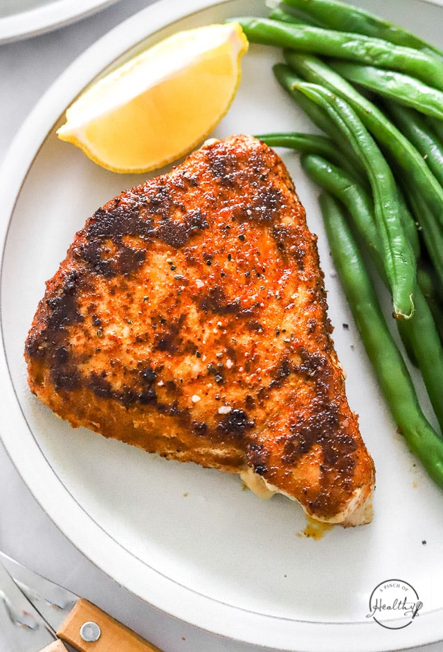 Blackened tuna steak on a plate with green beans shot closeup
