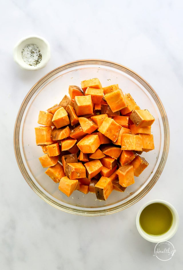 Seasoning the sweet potatoes in a mixing bowl