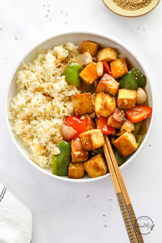 Styled sweet and sour tofu in a bowl with rice and chopsticks