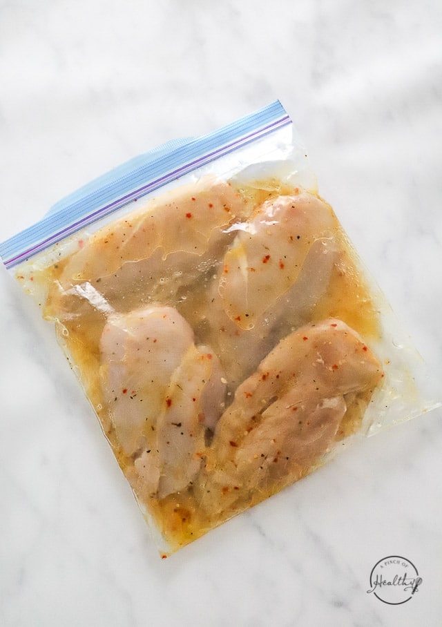 Raw chicken breast covered in dressing in sealed bag