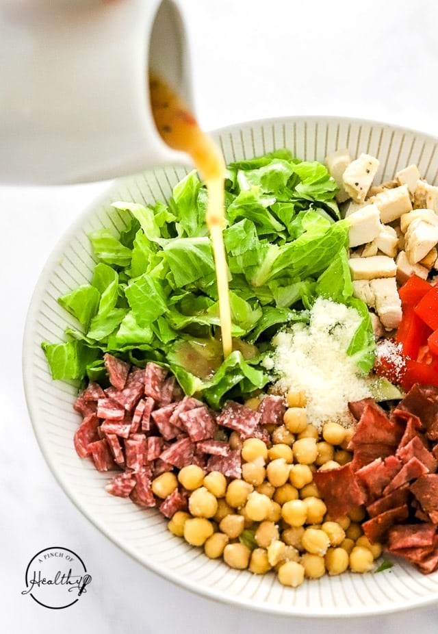 pouring Italian dressing on Jennifer Aniston salad