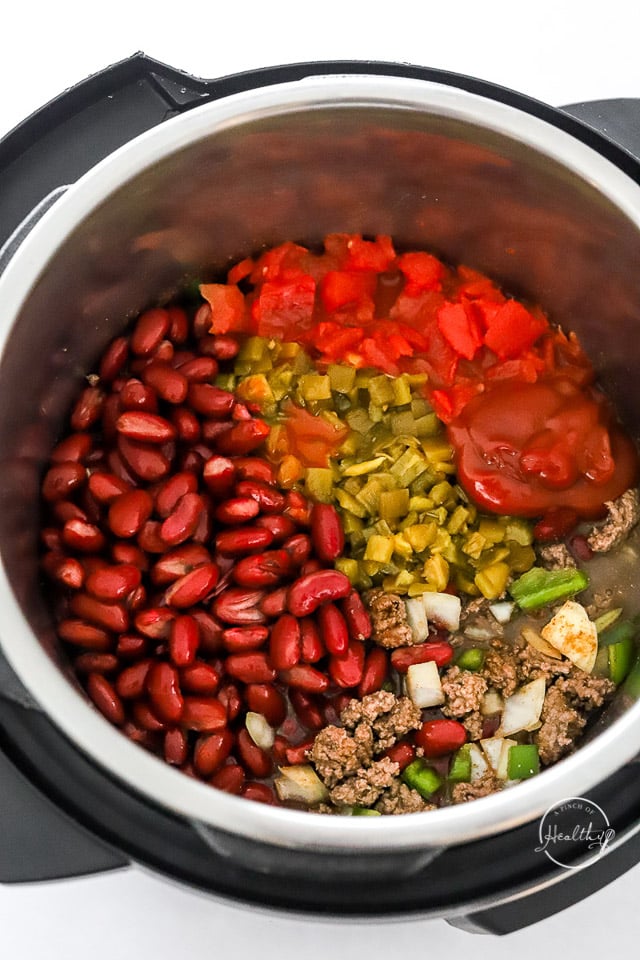adding beans and tomatoes to Instant Pot chili