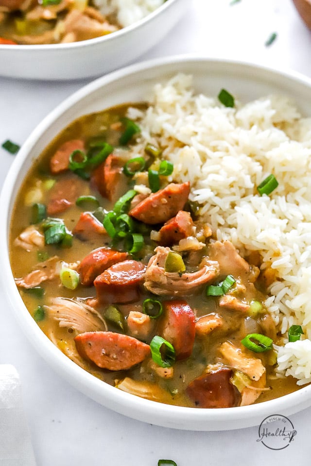 Chicken and sausage gumbo closeup in a white bowl with rice