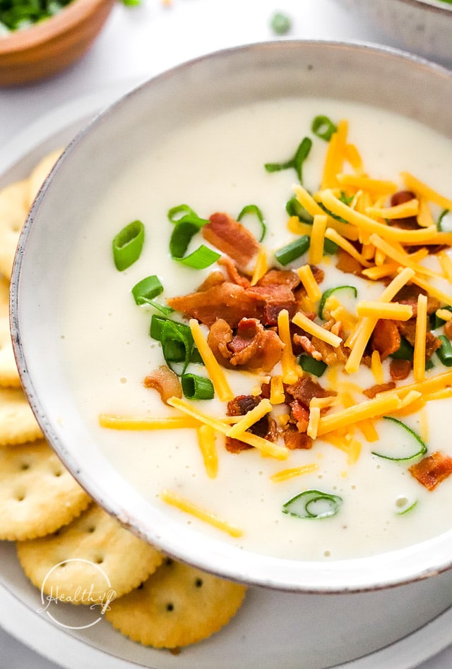 Instant Pot Potato Soup in a bowl with cheese, bacon and chives closeup