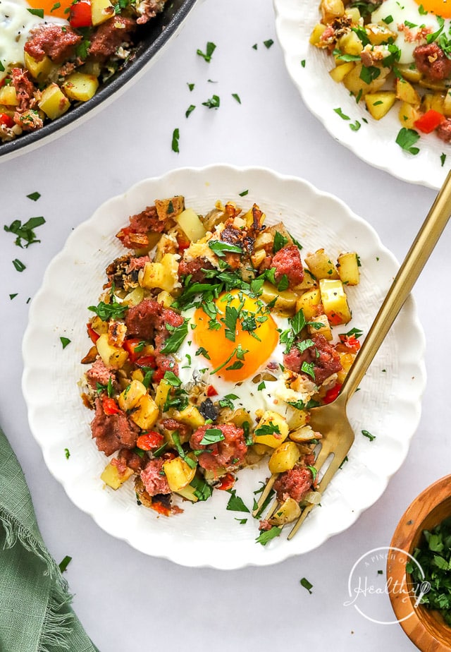 Corned Beef Hash with eggs on a white plate with fork