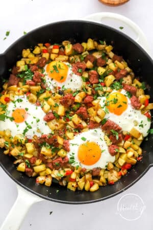 corned beef hash with baked eggs on top in a cast iron skillet