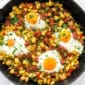 corned beef hash with baked eggs on top in a cast iron skillet