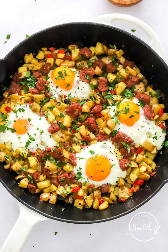 corned beef hash with baked eggs on top in a cast iron skillet