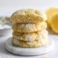 Lemon Crinkle Cookies stacked vertically on a white marble dish