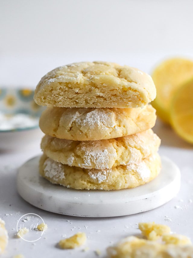 Lemon Crinkle Cookies stacked vertically on a white marble dish