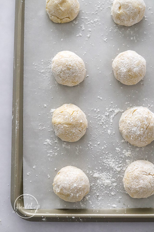 raw lemon crinkle cookies on a lined baking sheet