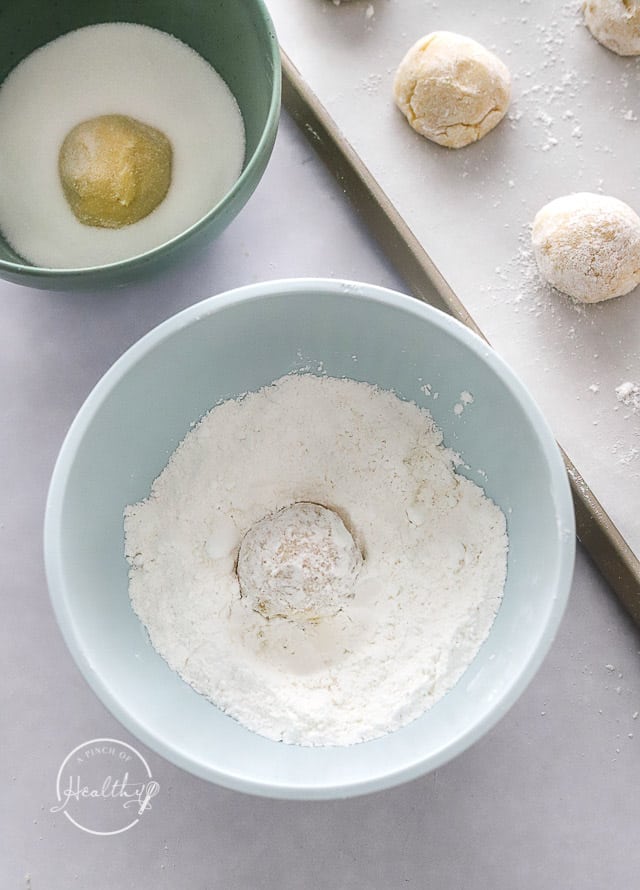 rolling raw cookies in sugar