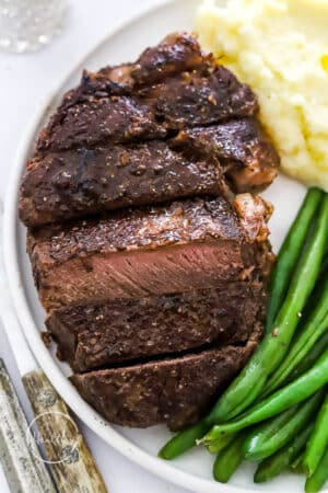 cast iron filet mignon on a plate with green beans and mashed potatoes