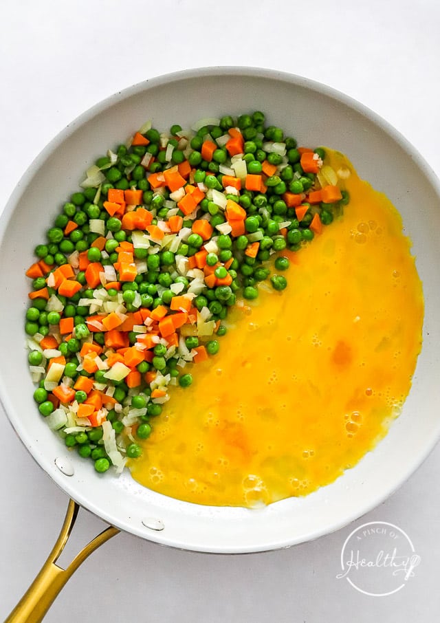 scrambling eggs with veggies to make tofu fried rice