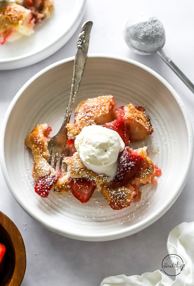 Strawberry Cobbler in a bowl with spoon and ice cream