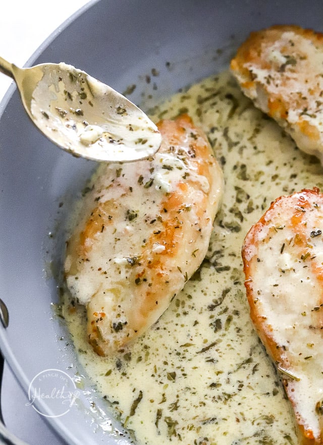 spooning sauce over chicken in a pan