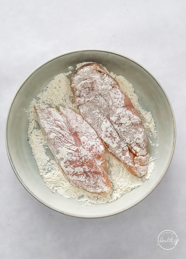 dipping raw chicken in flour