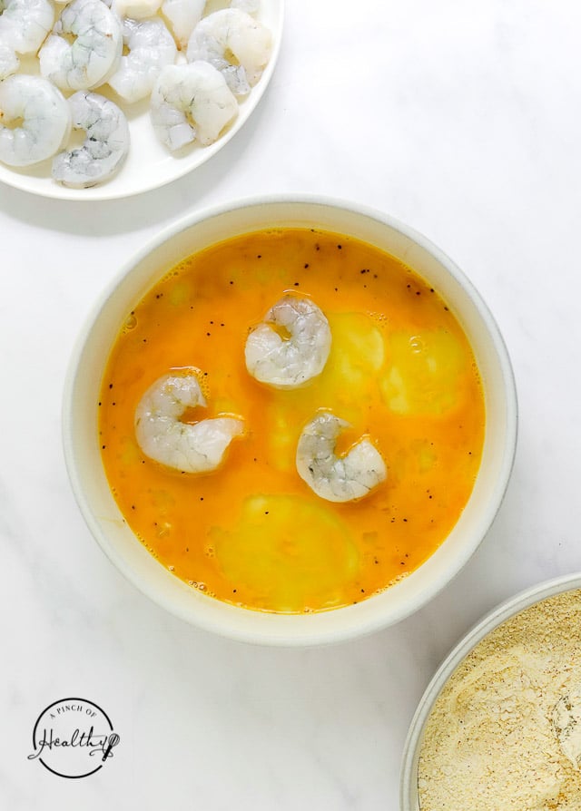 dipping raw shrimp in egg wash