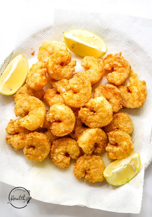 fried shrimp on a plate with lemon slices