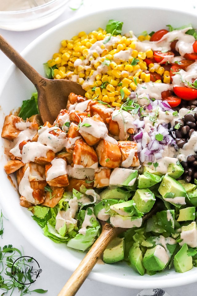 BBQ Chicken Salad shot closeup with a wood utensils in a white bowl