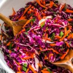 Red Cabbage Slaw in a serving bowl with wooden serving spoons