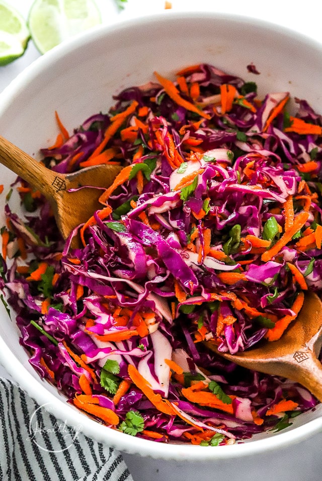 Red Cabbage Slaw in a serving bowl with wooden serving spoons