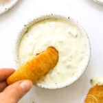 hand dipping fish stick into tartar sauce