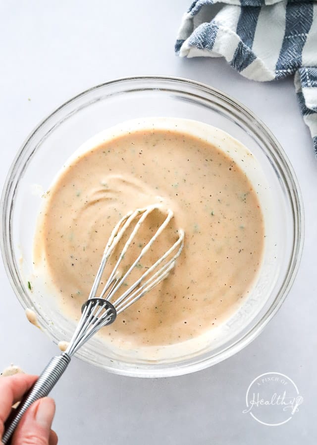 whisking creamy dressing in a mixing bowl