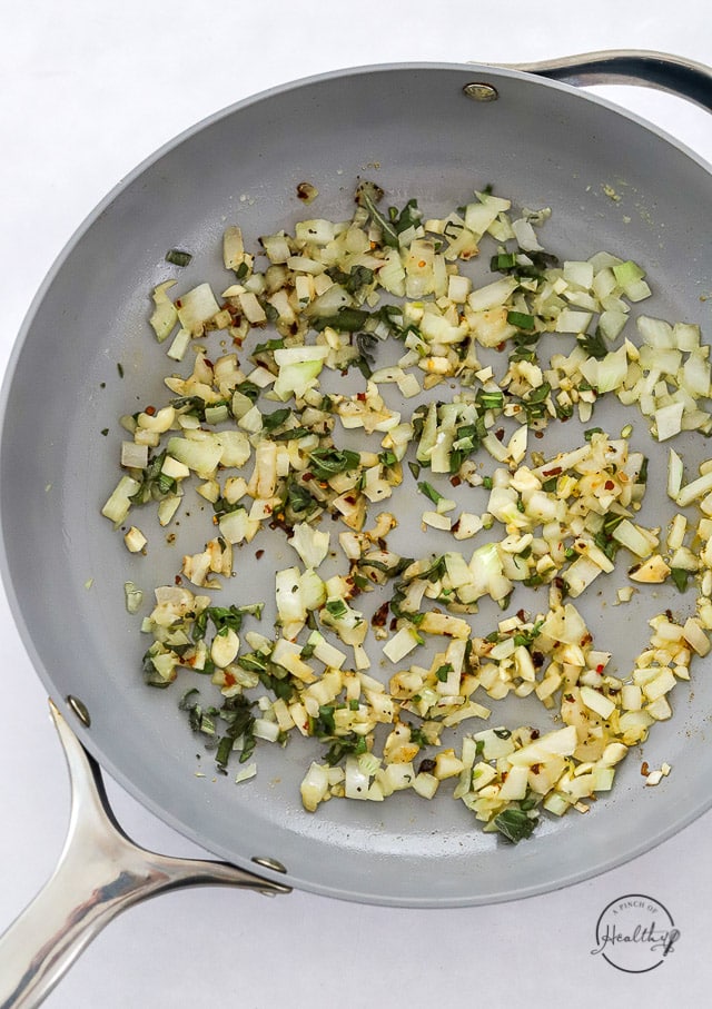 cooking onions garlic and herbs in a pan
