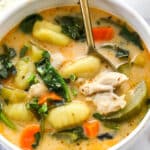 Chicken Gnocchi Soup closeup in white bowl with spoon and a side of sliced bread
