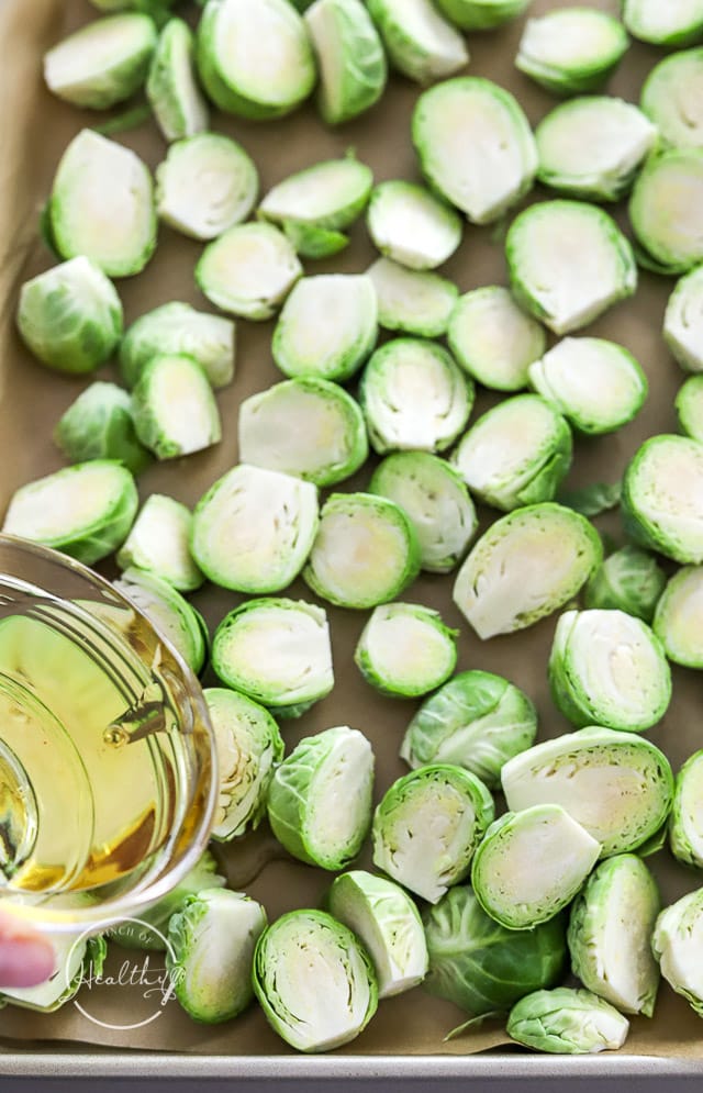 Pouring oil over sliced Brussels sprouts