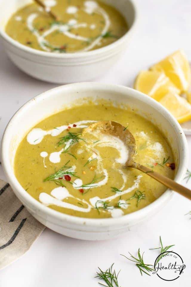 asparagus soup in a white bowl with a gold spoon