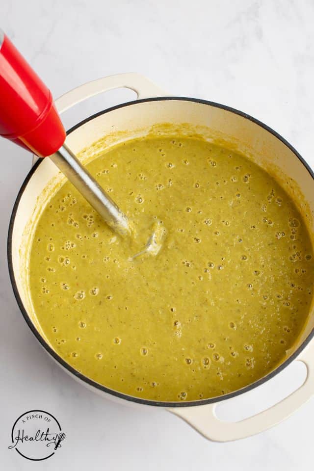 an immersion blender in the pot of asparagus soup