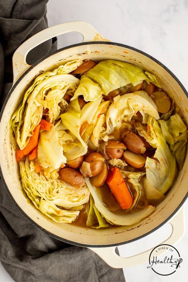 cabbage, potatoes, and carrots cooking in the corned beef liquid in a Dutch oven