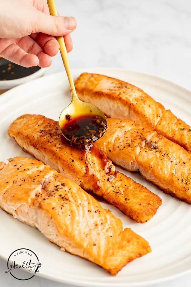 Glaze being poured over cooked salmon