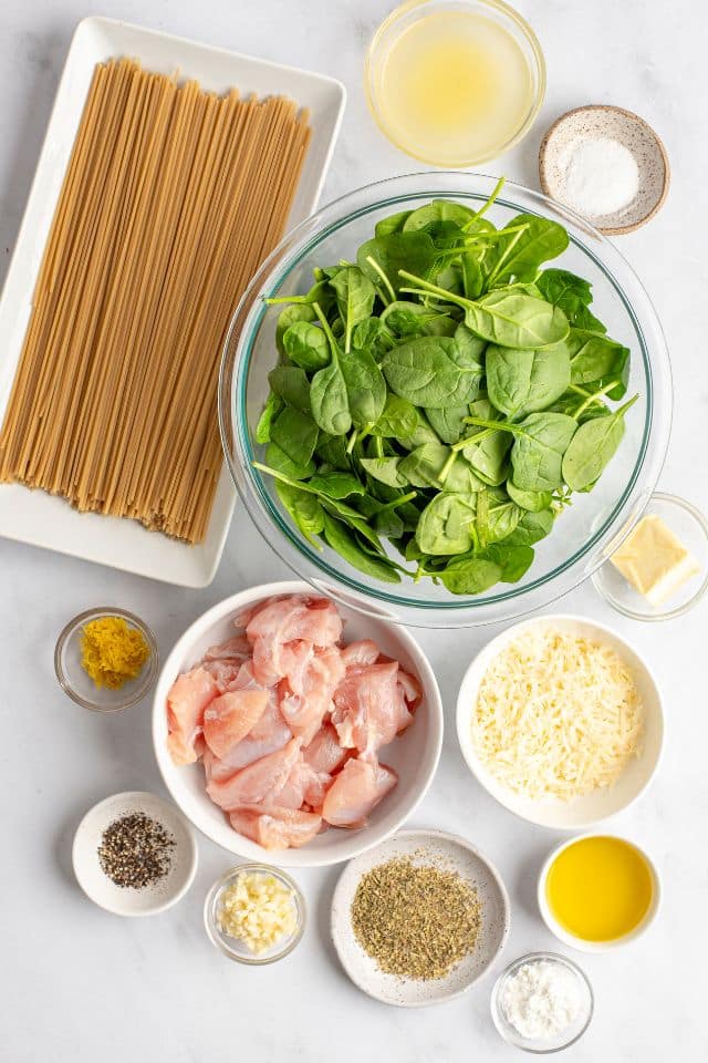 ingredients for lemon chicken pasta in separate bowls on a white background