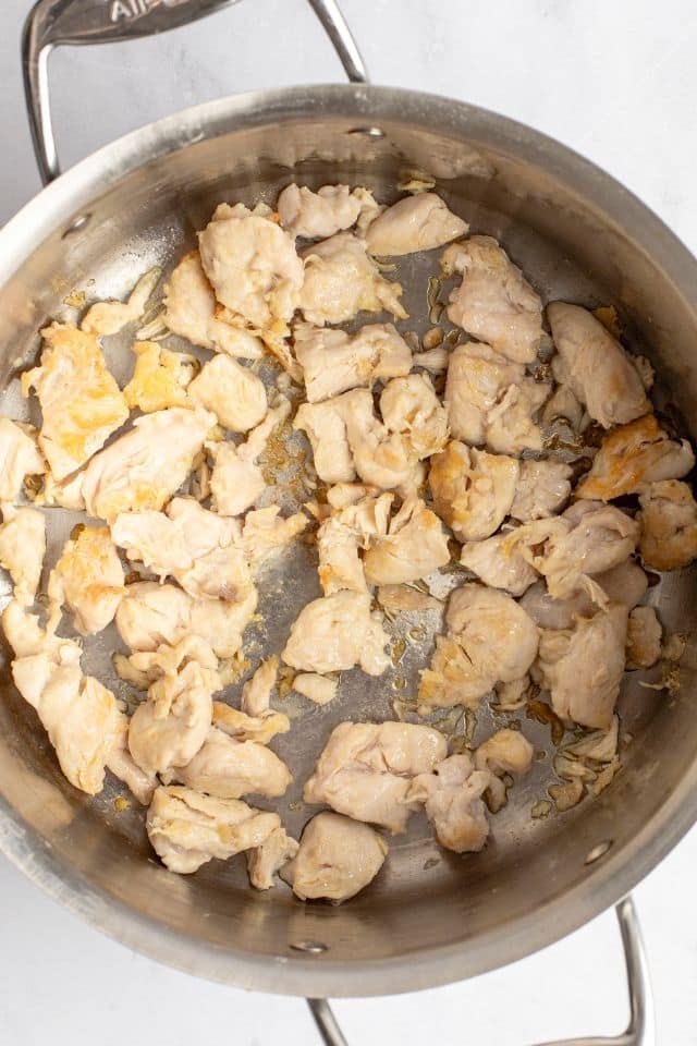chicken in a metal pan being cooked.