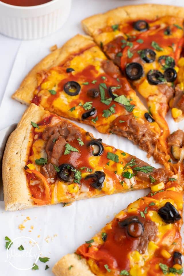 Cooked Mexican Pizza cut into slices on a white background