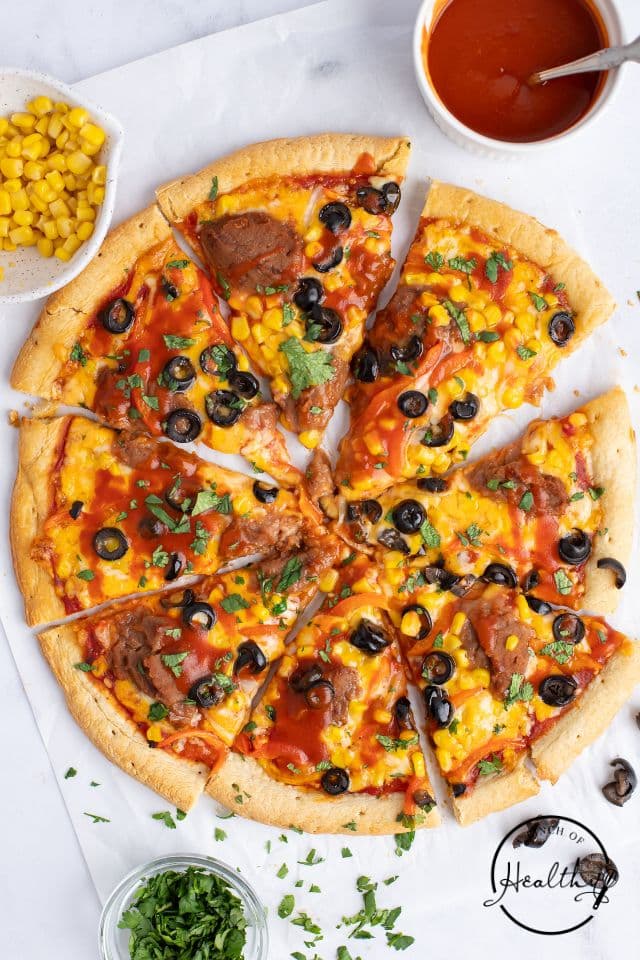 Mexican Pizza on a white background cut into slices.