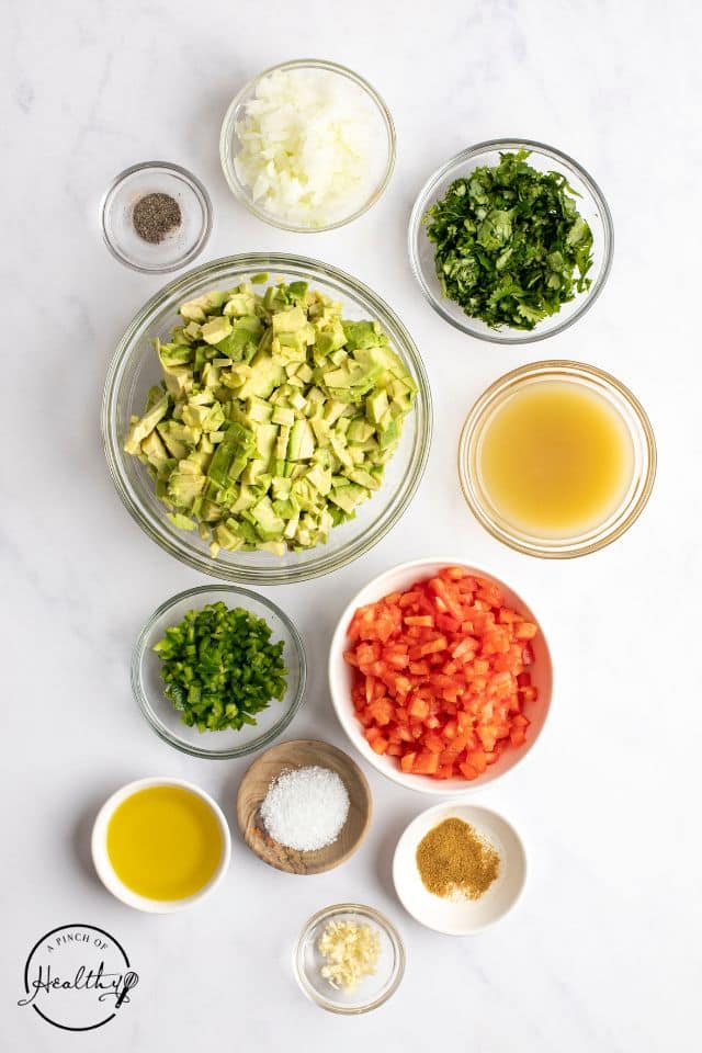 ingredients for avocado salsa in separate bowls on a white background shot from above.