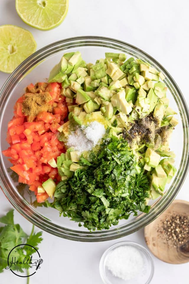 ingredients for avocado salsa in a large glass bowl prior to being stirred together