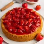 Cheesecake with strawberries on top and fresh strawberries around it