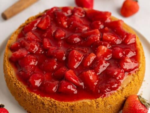 Cheesecake with strawberries on top and fresh strawberries around it