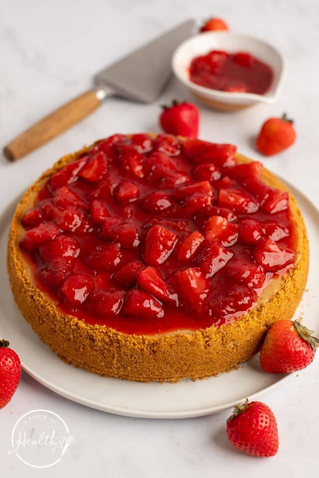 Cheesecake with strawberries on top and fresh strawberries around it