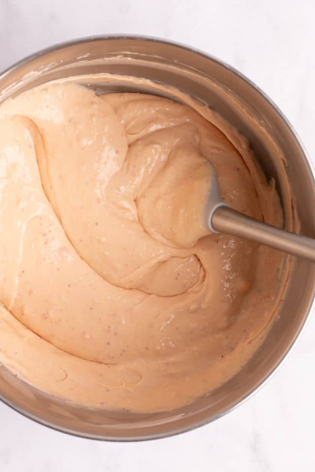 cheesecake batter mixed in a large bowl with a rubber spatula inside