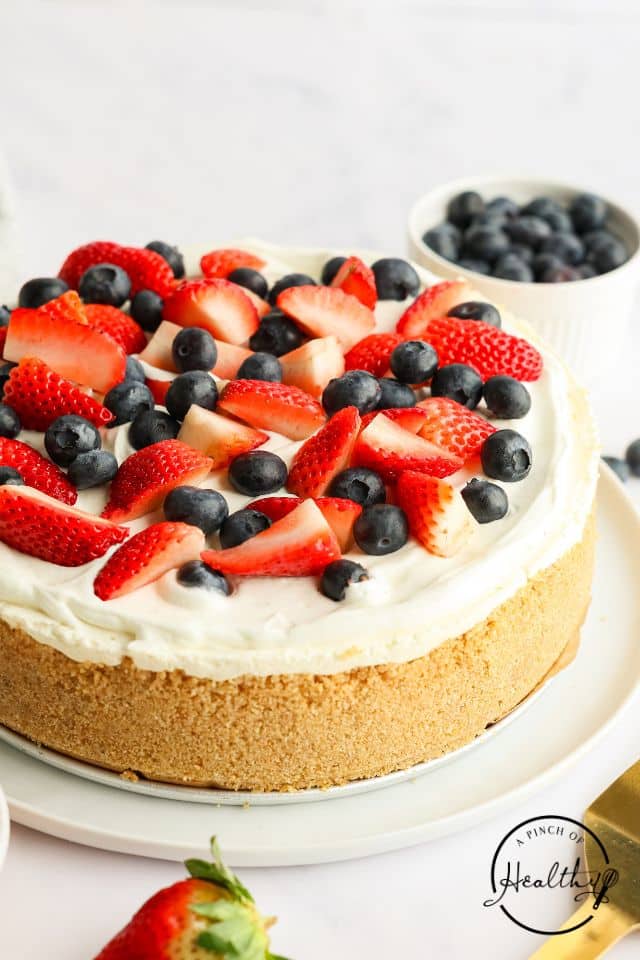 No Bake Cheesecake with fresh strawberries and blueberries on top and a graham cracker crust.