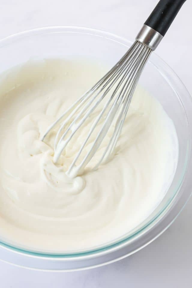 Whipping cream after being whipped with a whisk until medium peaks form.