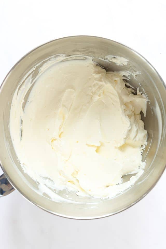 Cream cheese is a large mixing bowl after being beaten until it is smooth.