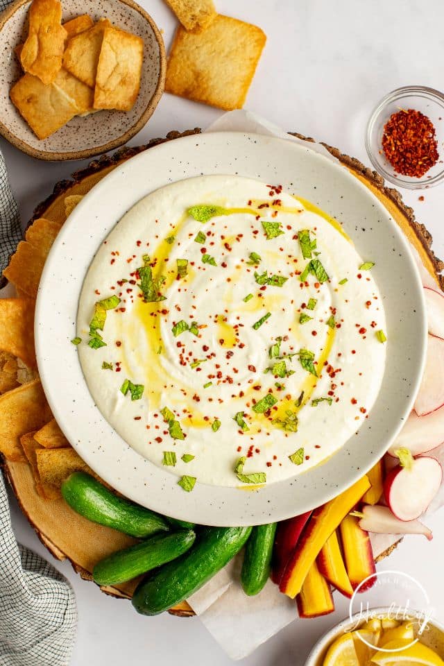 Whipped Feta Dip on a cutting board with vegetables and pita chips around the dish.