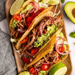 Brisket Tacos on a cutting board with lime wedges.